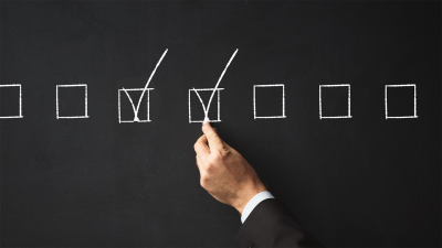 Hand marking a checkbox on a checklist to represent quality control and decision-making